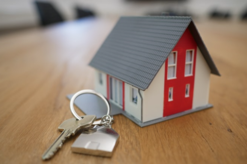 small red and white house, plans, magnifying glass and piggy bank