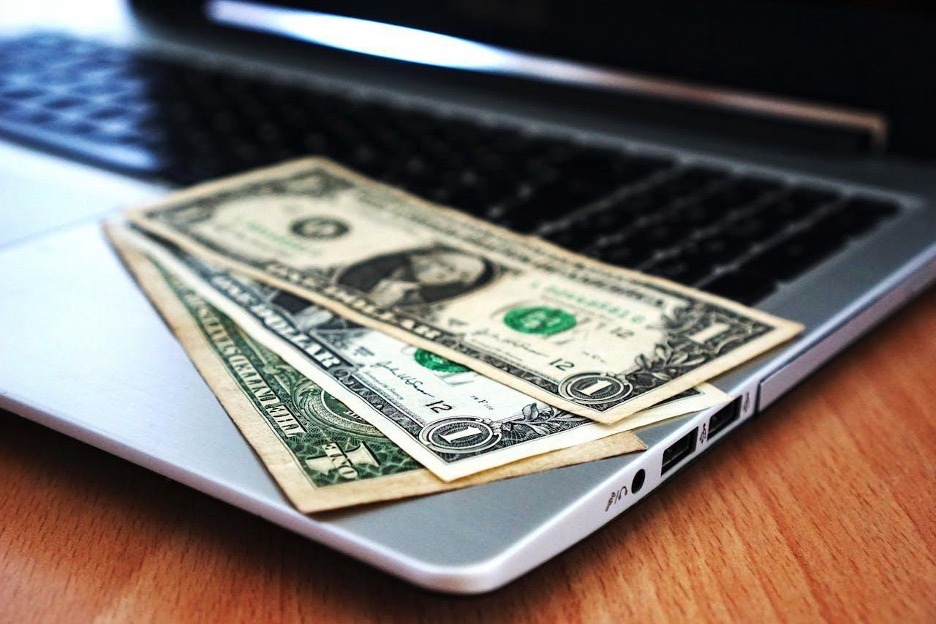 US dollar bills on top of a laptop