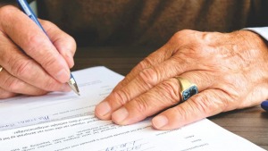 A man signing a document on a table