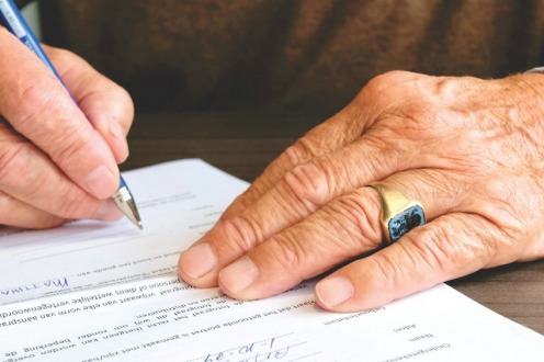 A man signing a document on a table